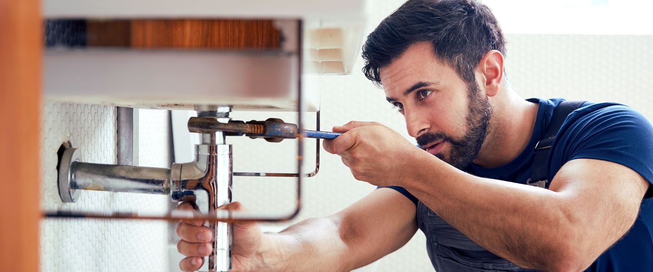 Instalator lucrând la sifonul de sub chiuveta de bucătărie